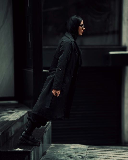 XAYWEAR black coat for women styled with a long fit and button detail worn with boots