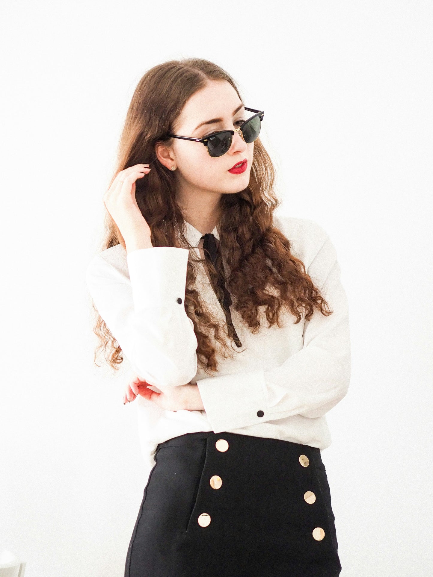 Woman wearing XAYWEAR black skirt with gold buttons paired with white blouse and sunglasses