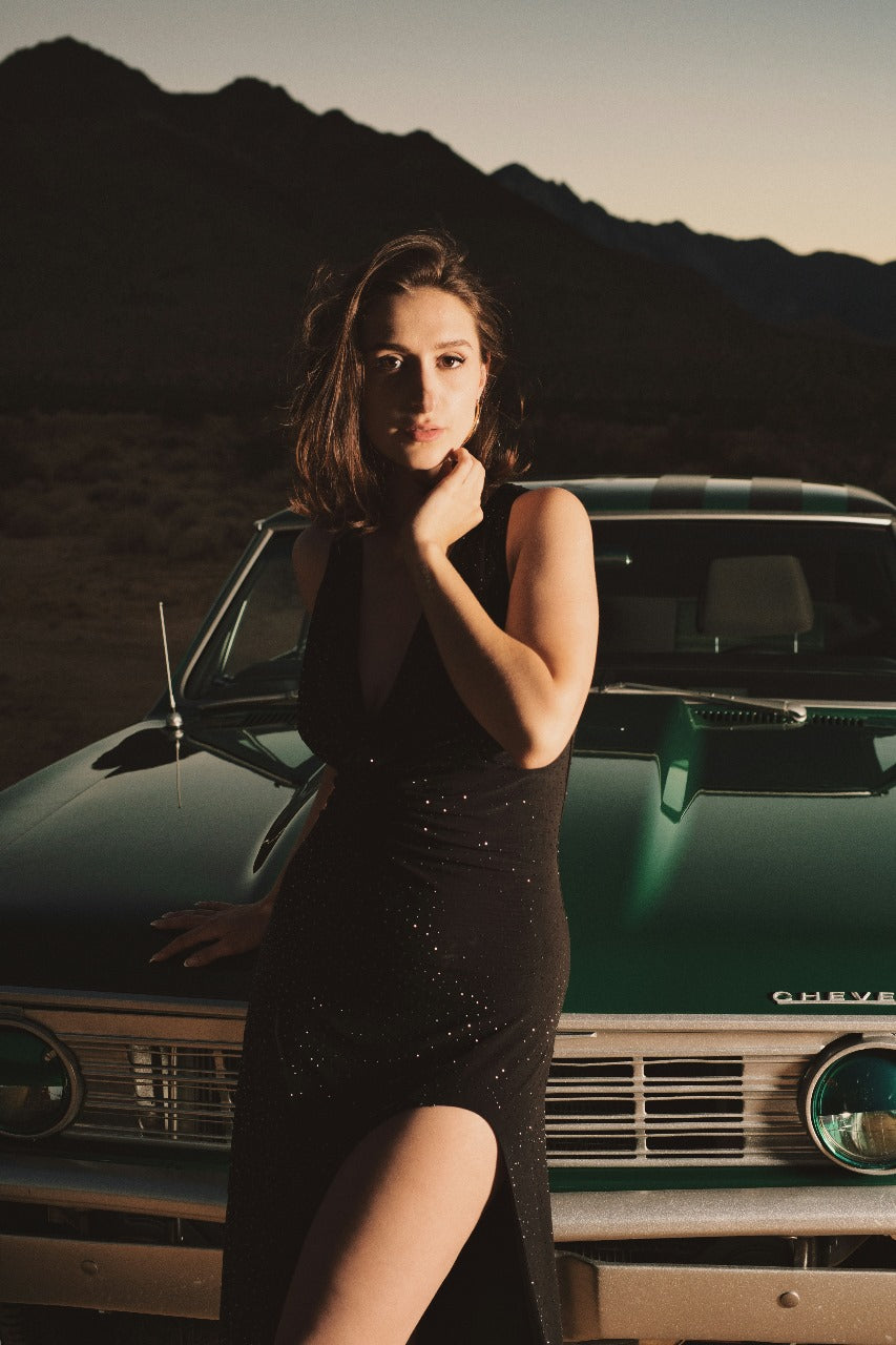 XAYWEAR black slit dress worn by woman posing on vintage green car with mountain background