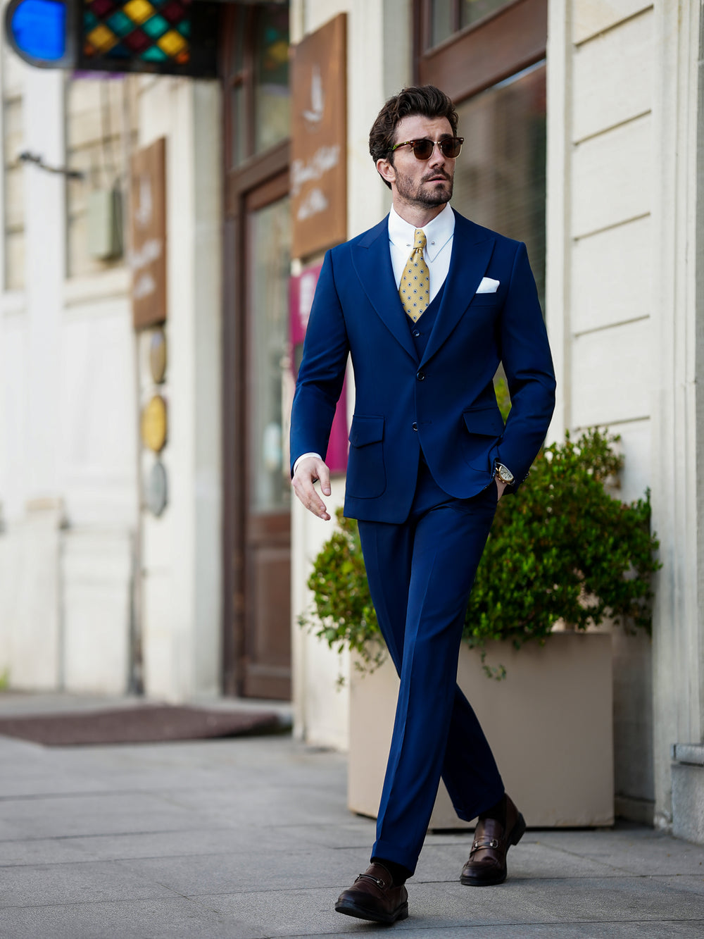XAYWEAR navy blue suit with white shirt and yellow tie, formal wear for men walking outdoors