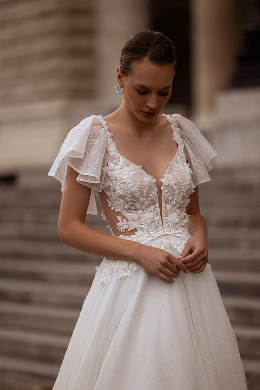 XAYWEAR elegant white bridal gown with lace bodice and flutter sleeves on model outdoors