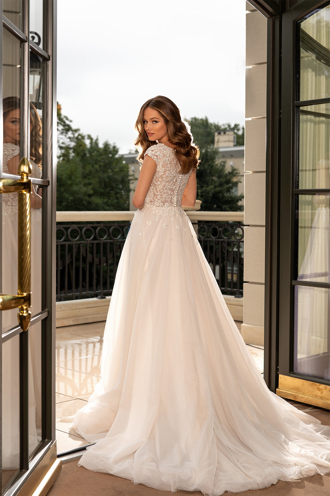XAYWEAR bridal gown wedding dress with lace bodice and flowing tulle skirt on balcony