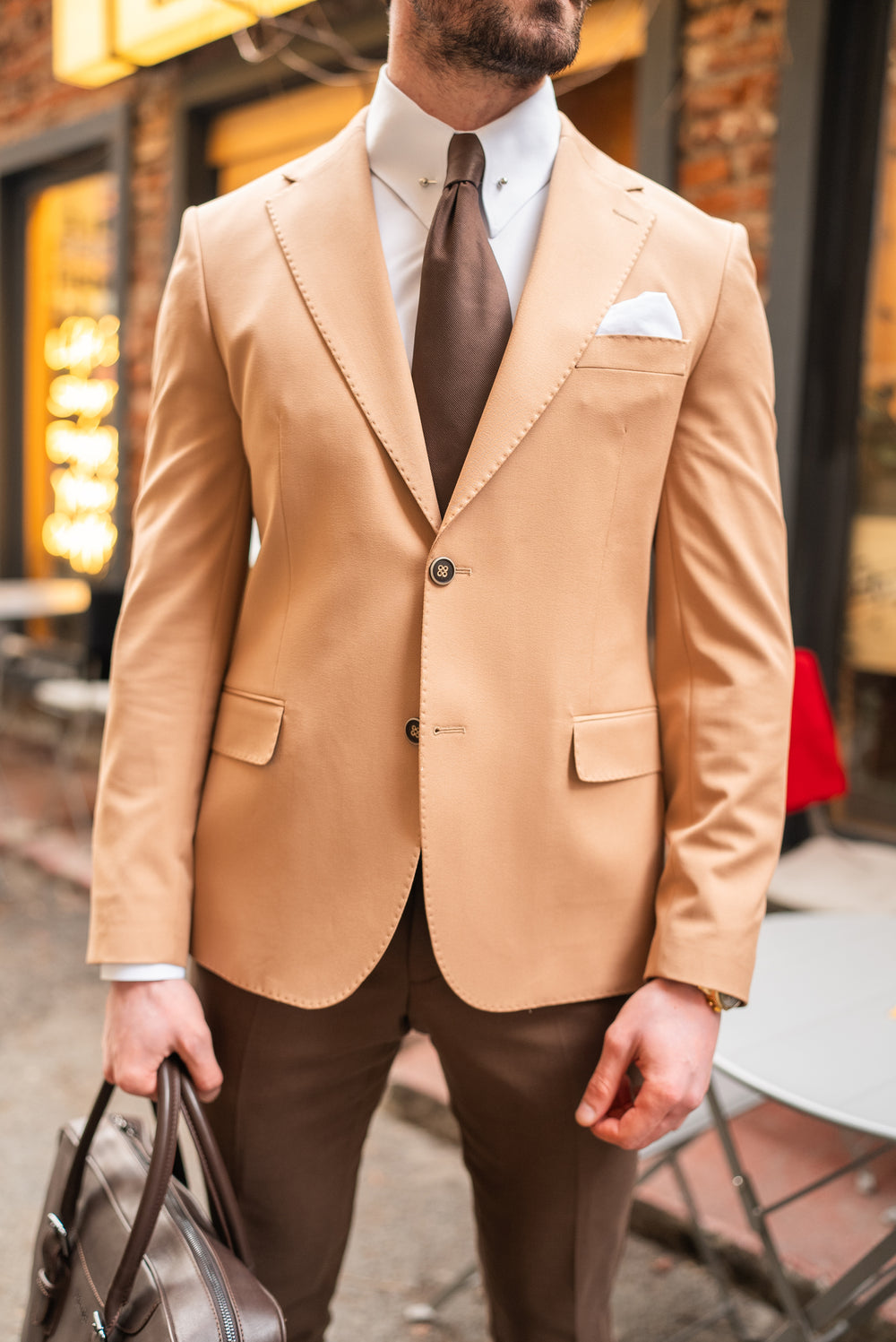 XAYWEAR beige suit for men with white shirt and brown tie, styled with brown pants and a leather bag