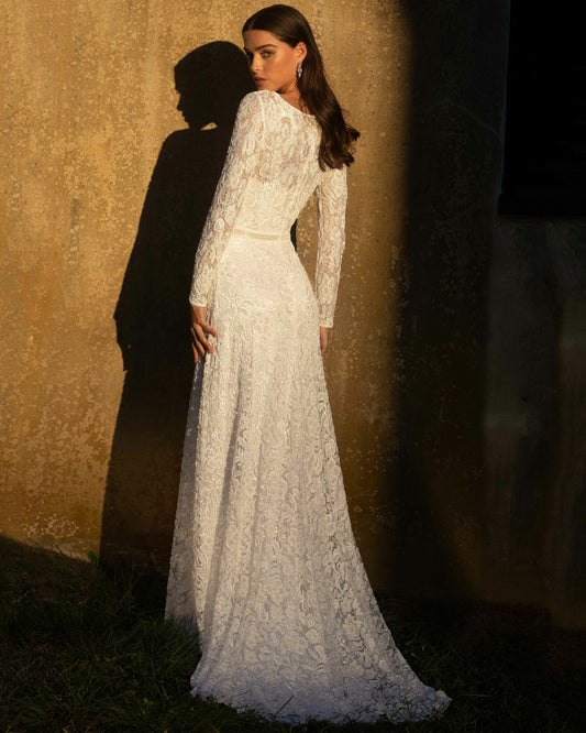 XAYWEAR white bridal gown with long lace sleeves and flowing skirt worn by model standing outdoors