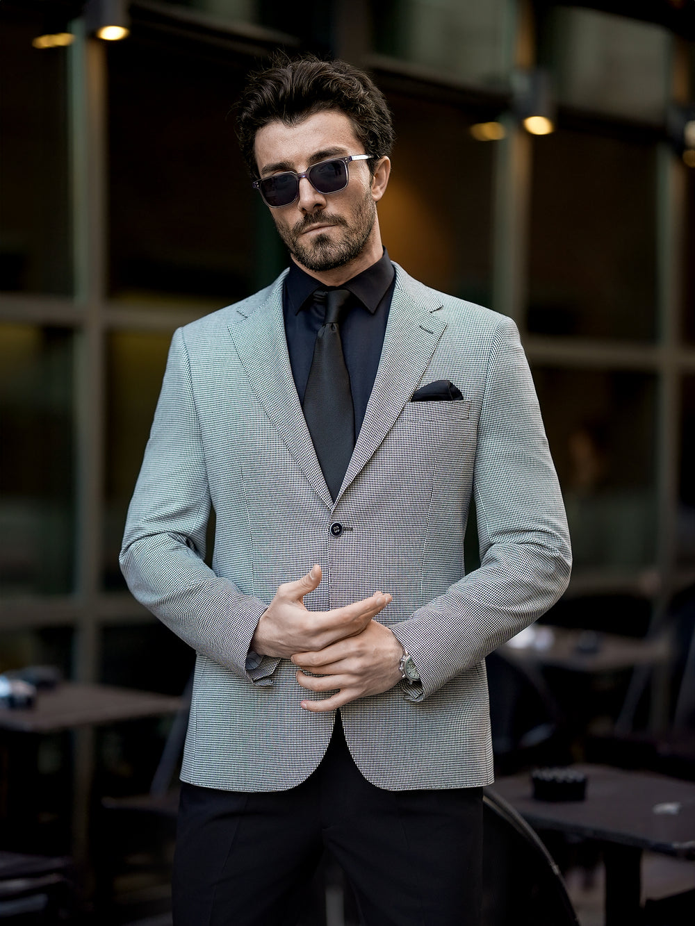 Man wearing XAYWEAR gray two piece suit for men with black shirt and tie outdoors