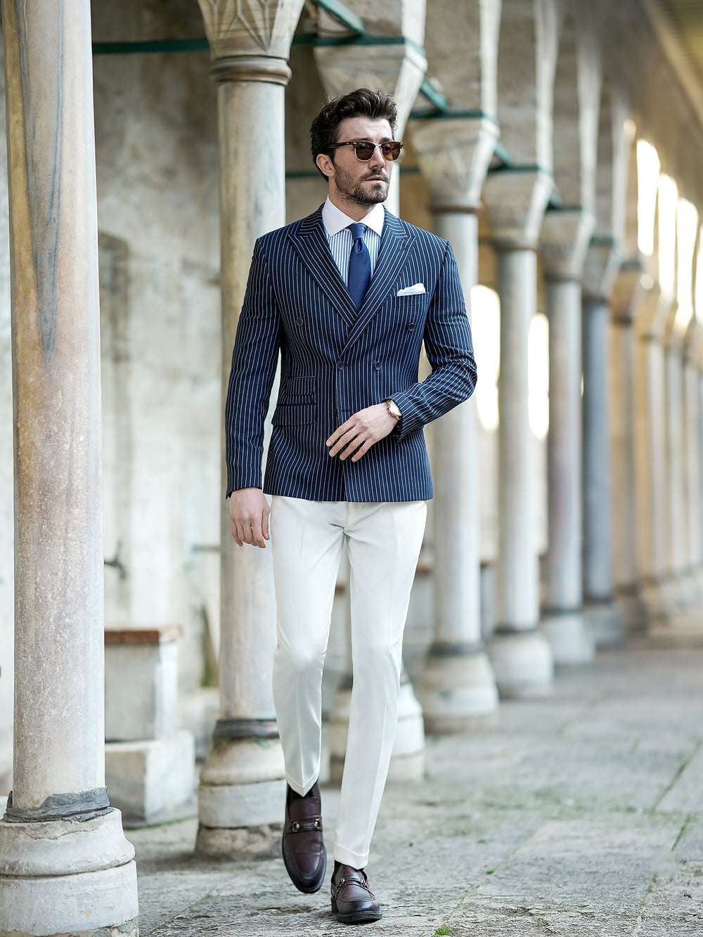 Stylish man wearing a navy pinstripe double-breasted blazer paired with white pants for a sophisticated look