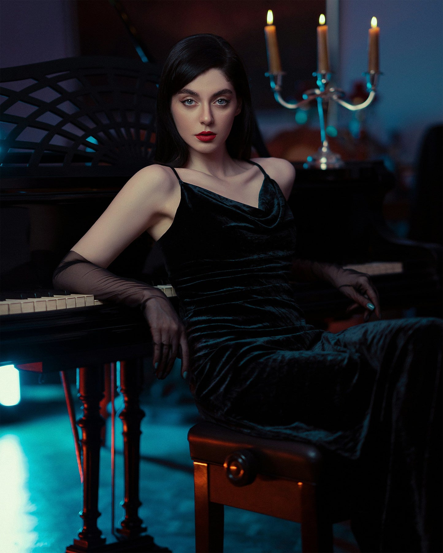Elegant model wearing a premium velvet evening gown, styled with black gloves and sitting at a piano