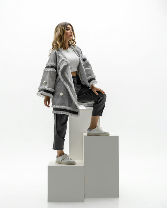 XAYWEAR gray fluffy women coat styled with black pants and white sneakers on model posing on white blocks