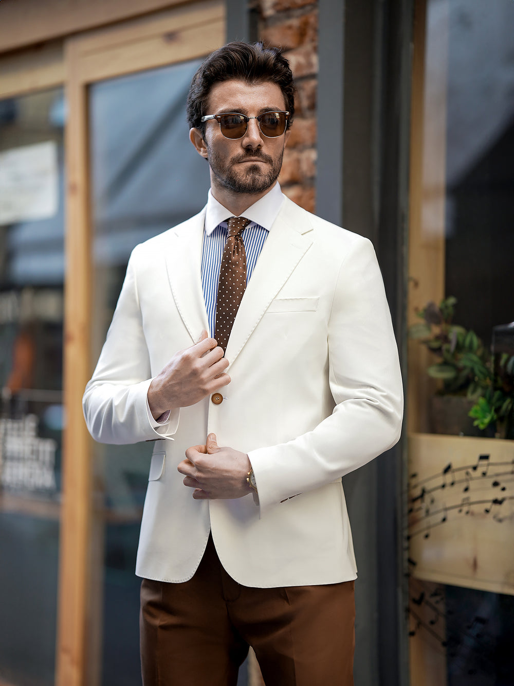 Man wearing a stylish white two piece suit for men by XAYWEAR with sunglasses and brown pants