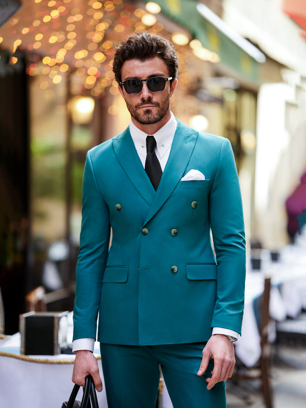 Man wearing a stylish teal double-breasted suit for men by XAYWEAR with black tie and sunglasses