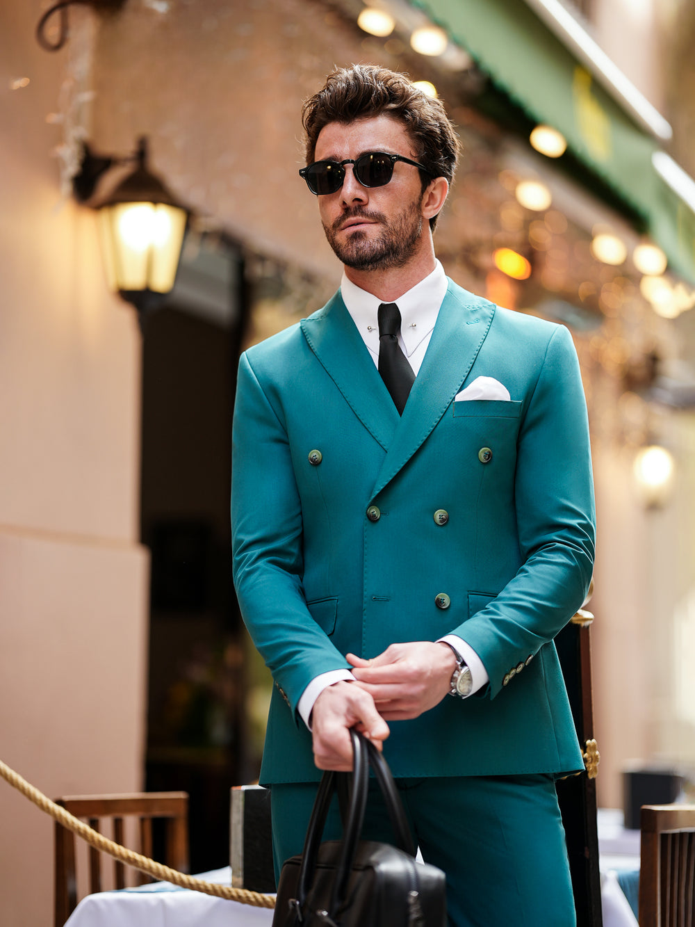 Man wearing teal double-breasted suit for men by XAYWEAR with black tie and sunglasses