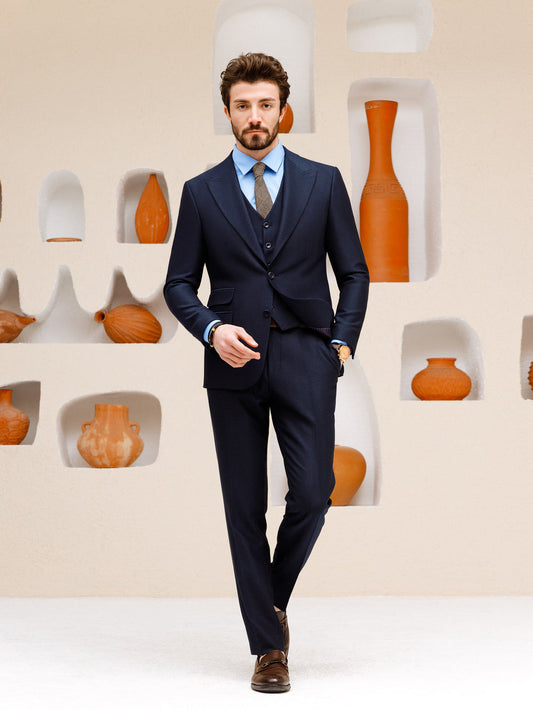 XAYWEAR navy blue suit set for men with vest and tie modeled by man against decorative wall