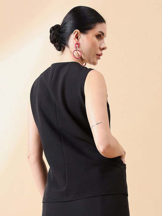 XAYWEAR black sleeveless waistcoat top with clean lines worn by woman with dark hair and pink earrings