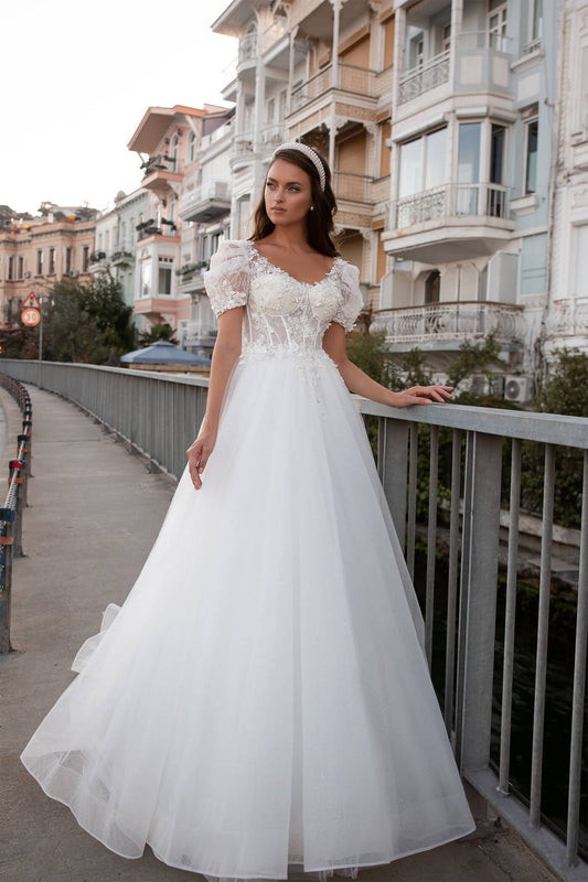 XAYWEAR elegant wedding dress gown with puff sleeves and lace bodice standing outdoors by railing