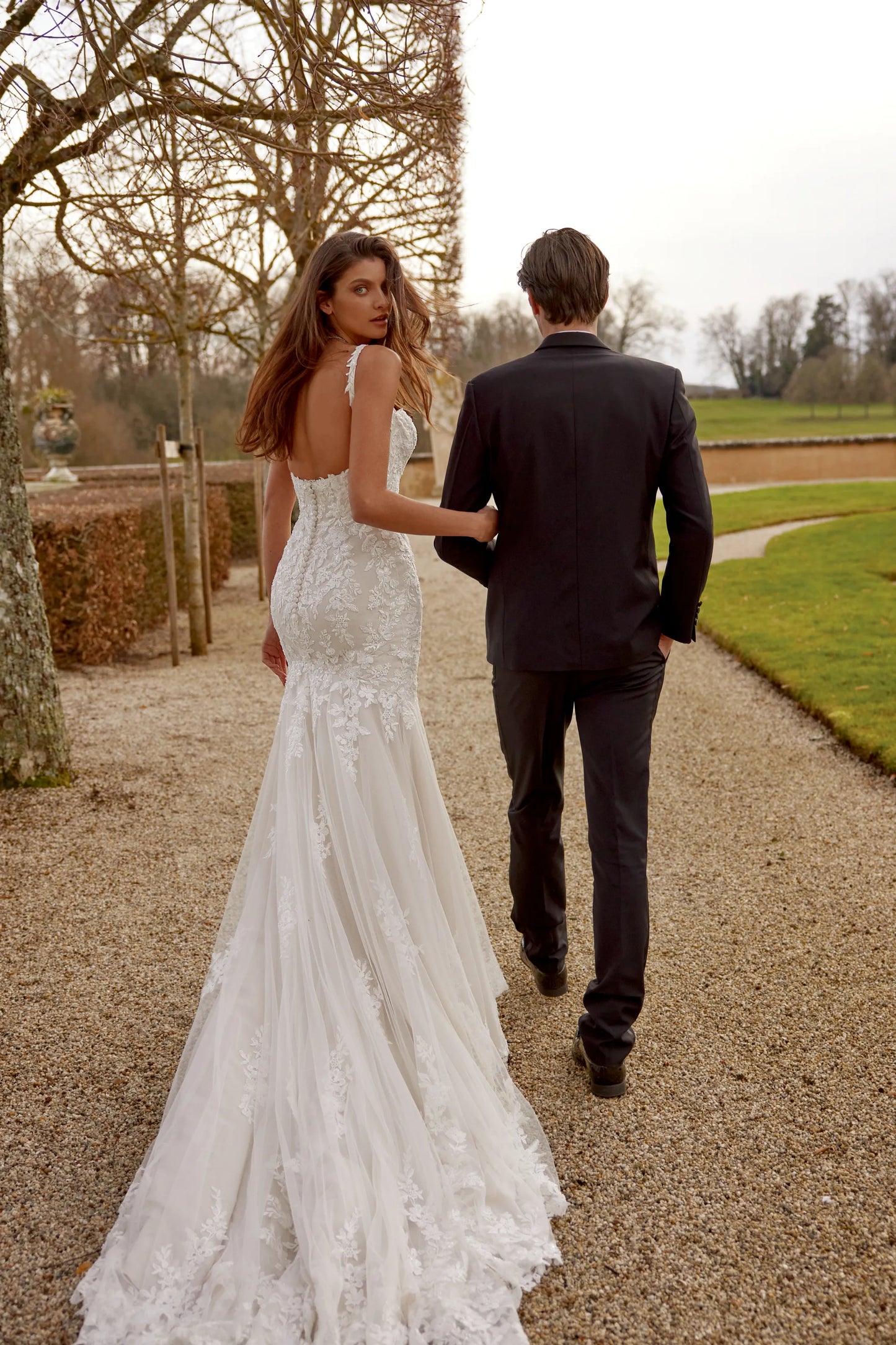 XAYWEAR white wedding dress with lace details and long train worn by bride outdoors