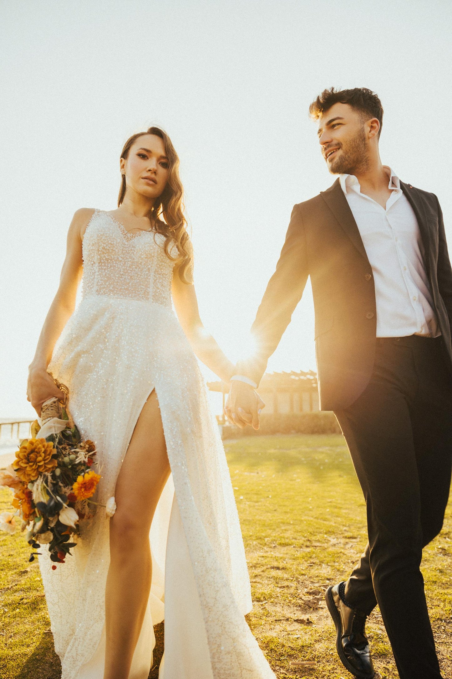Bride wearing XAYWEAR Wedding Gown with lace details and thigh slit holding bouquet outdoors