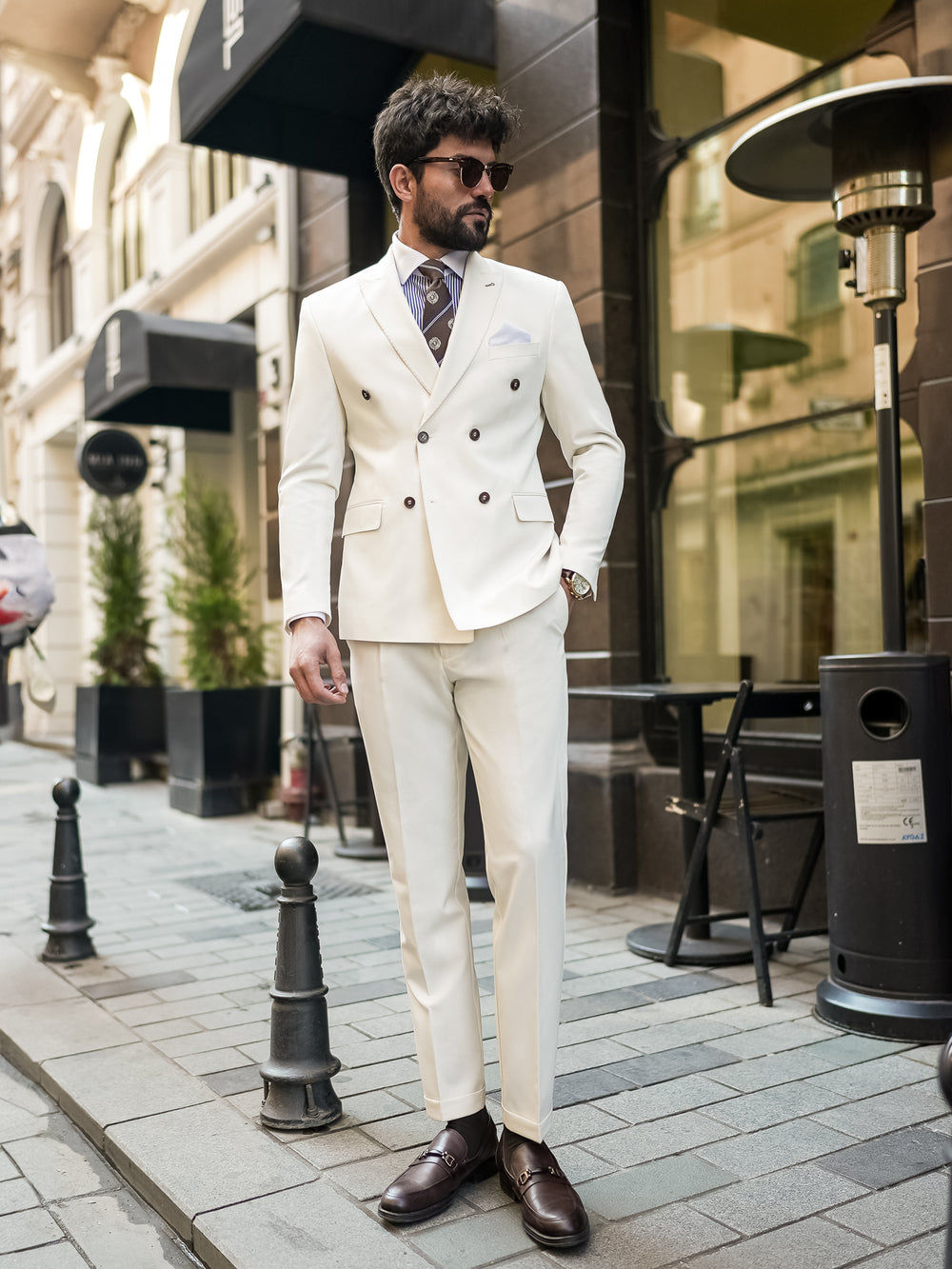 Man wearing a stylish white suit for men by XAYWEAR paired with a patterned tie and brown dress shoes
