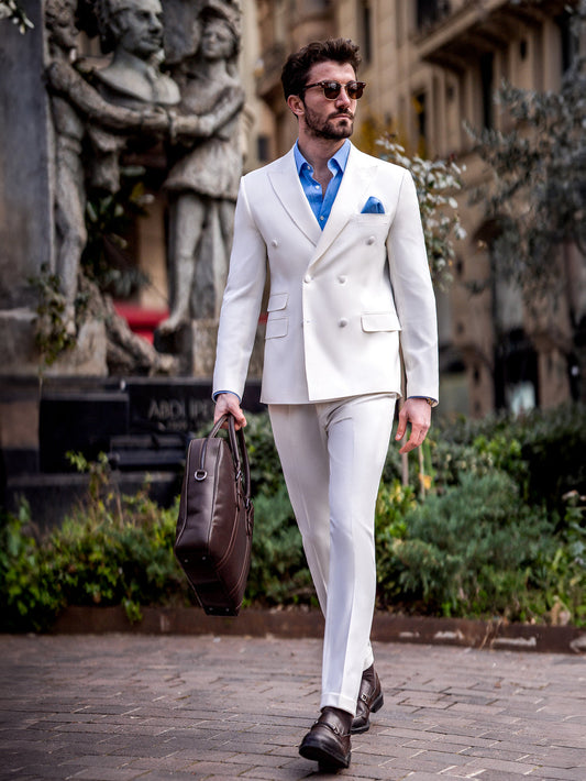 Man wearing a white suit for men by XAYWEAR with double-breasted blazer and blue shirt walking outdoors