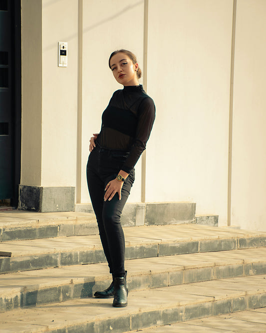 Elegant women black top by XAYWEAR styled with black pants and boots on outdoor steps