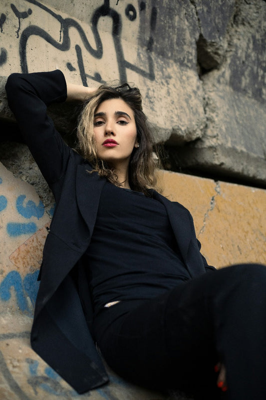 Stylish women blazer by XAYWEAR in black worn by model leaning against graffiti wall