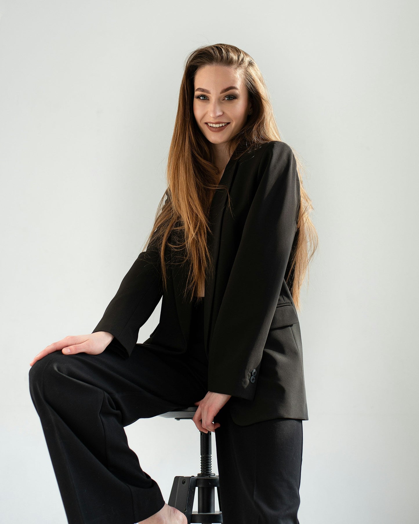Woman wearing XAYWEAR black suit sitting on a stool showcasing women formal attire