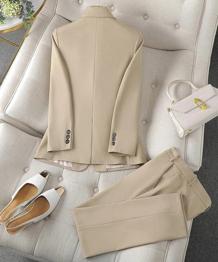 Beige suit for women by XAYWEAR displayed with matching pants and white heels on a tufted sofa