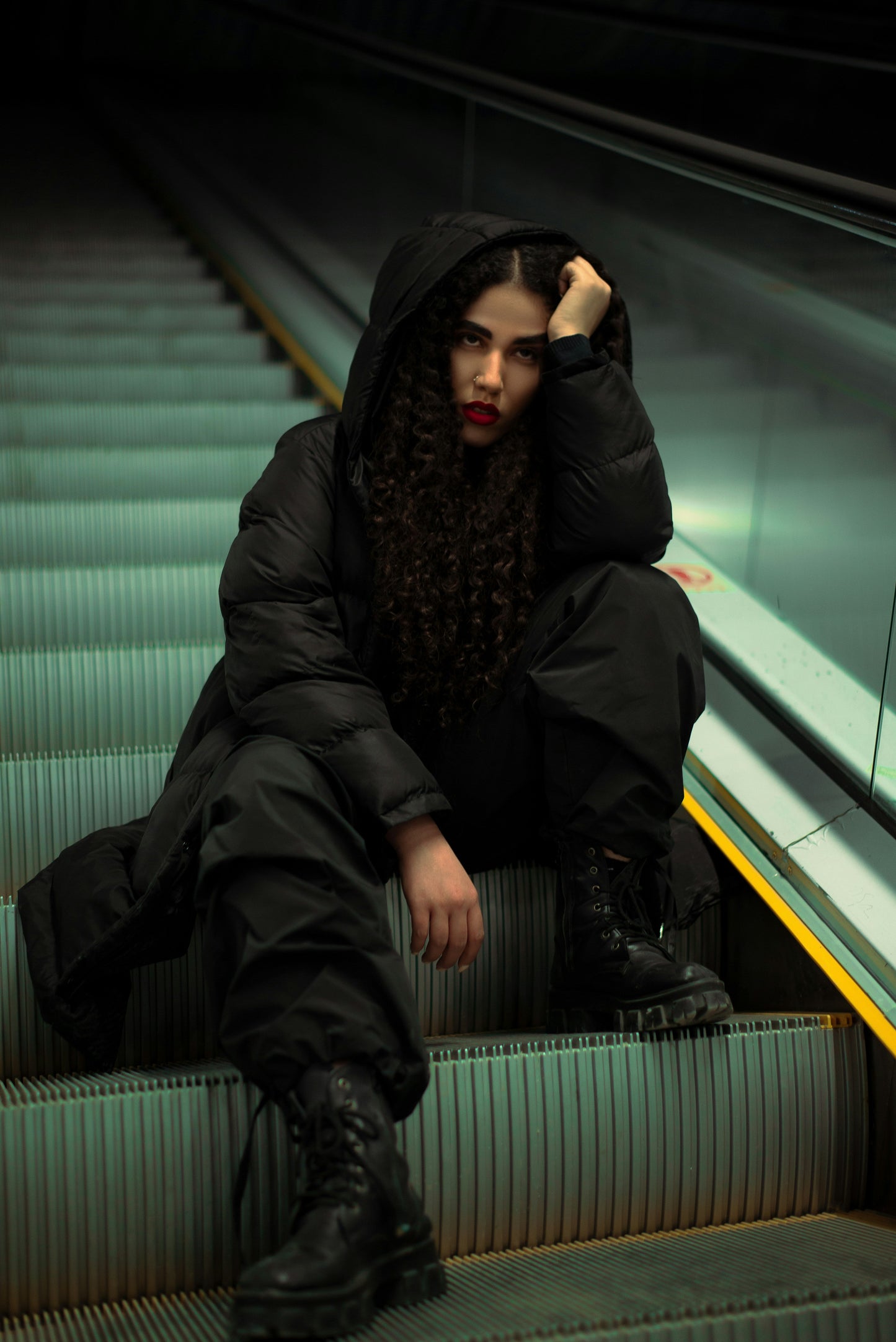 XAYWEAR premium black hooded puffer jacket worn by model sitting on stairs with urban backdrop