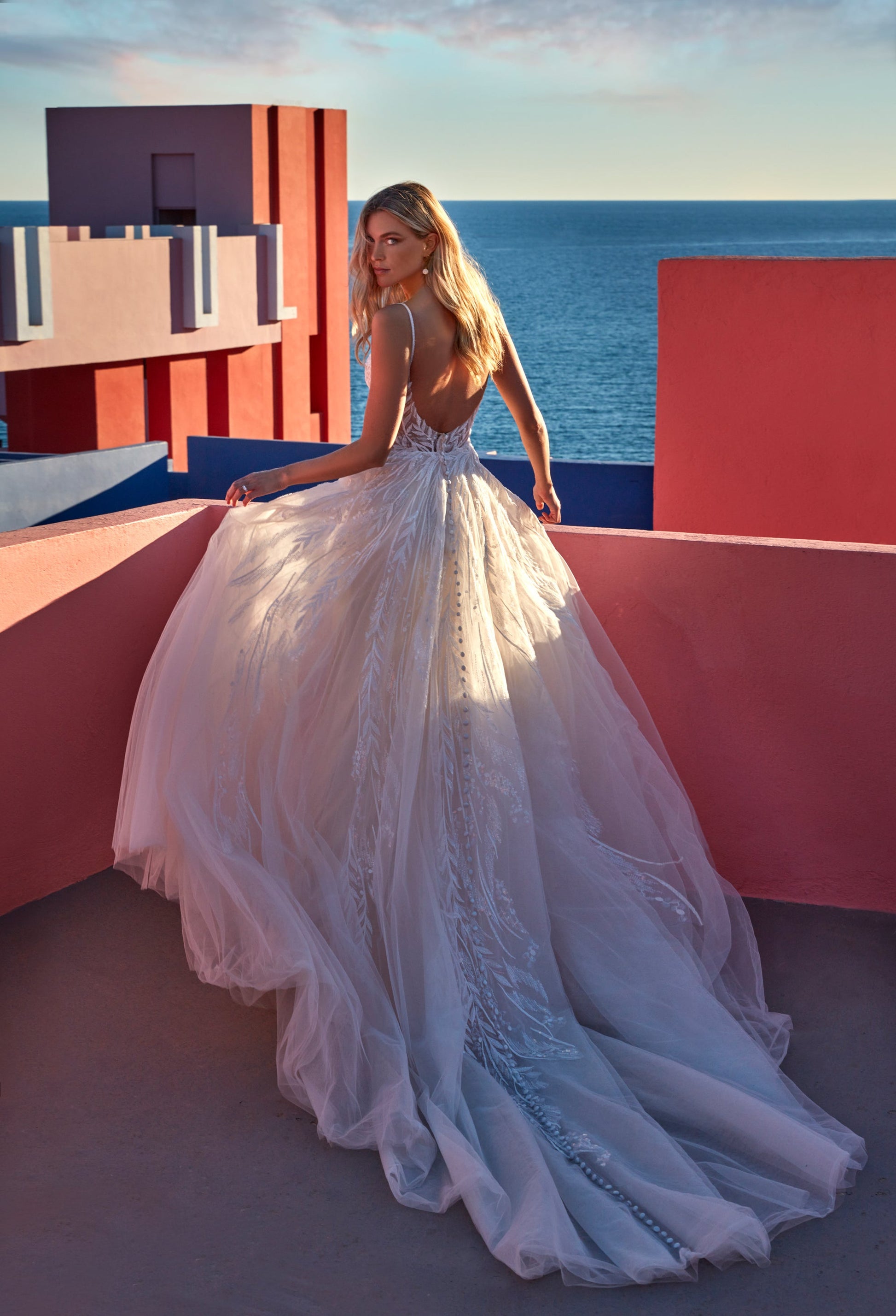 XAYWEAR elegant white wedding dress gown with detailed lace and long flowing train by the seaside