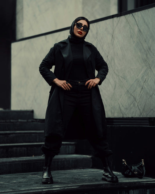 Stylish woman wearing a black coat for women from XAYWEAR with matching black boots and sunglasses