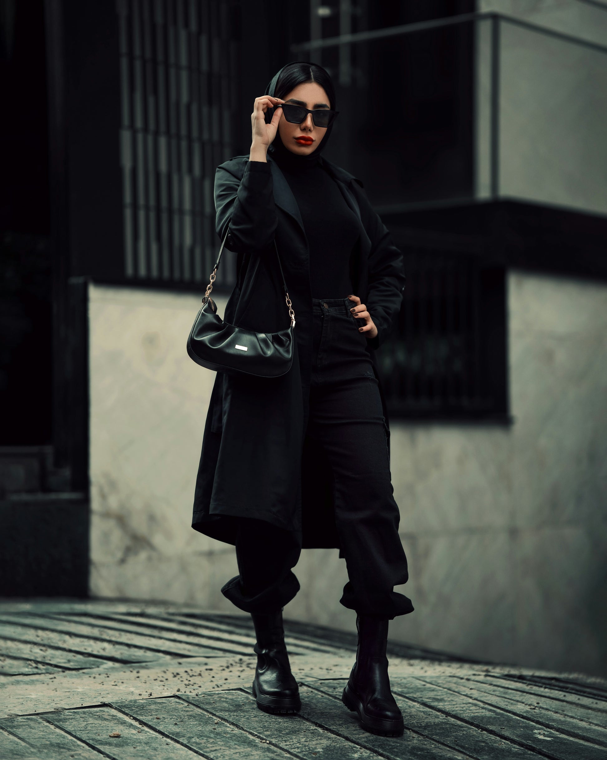 Stylish black coat for women by XAYWEAR worn with sunglasses and black outfit in urban setting
