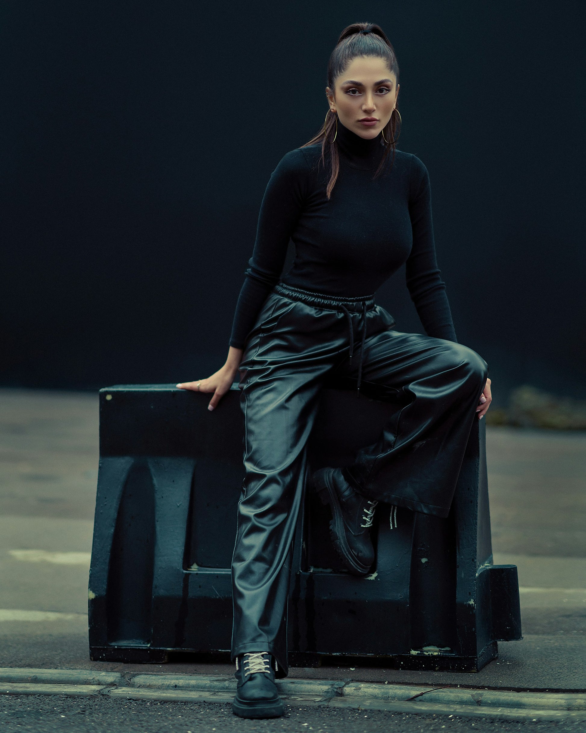 Woman modeling black leather women outfit with high-waisted pants and black long sleeve top