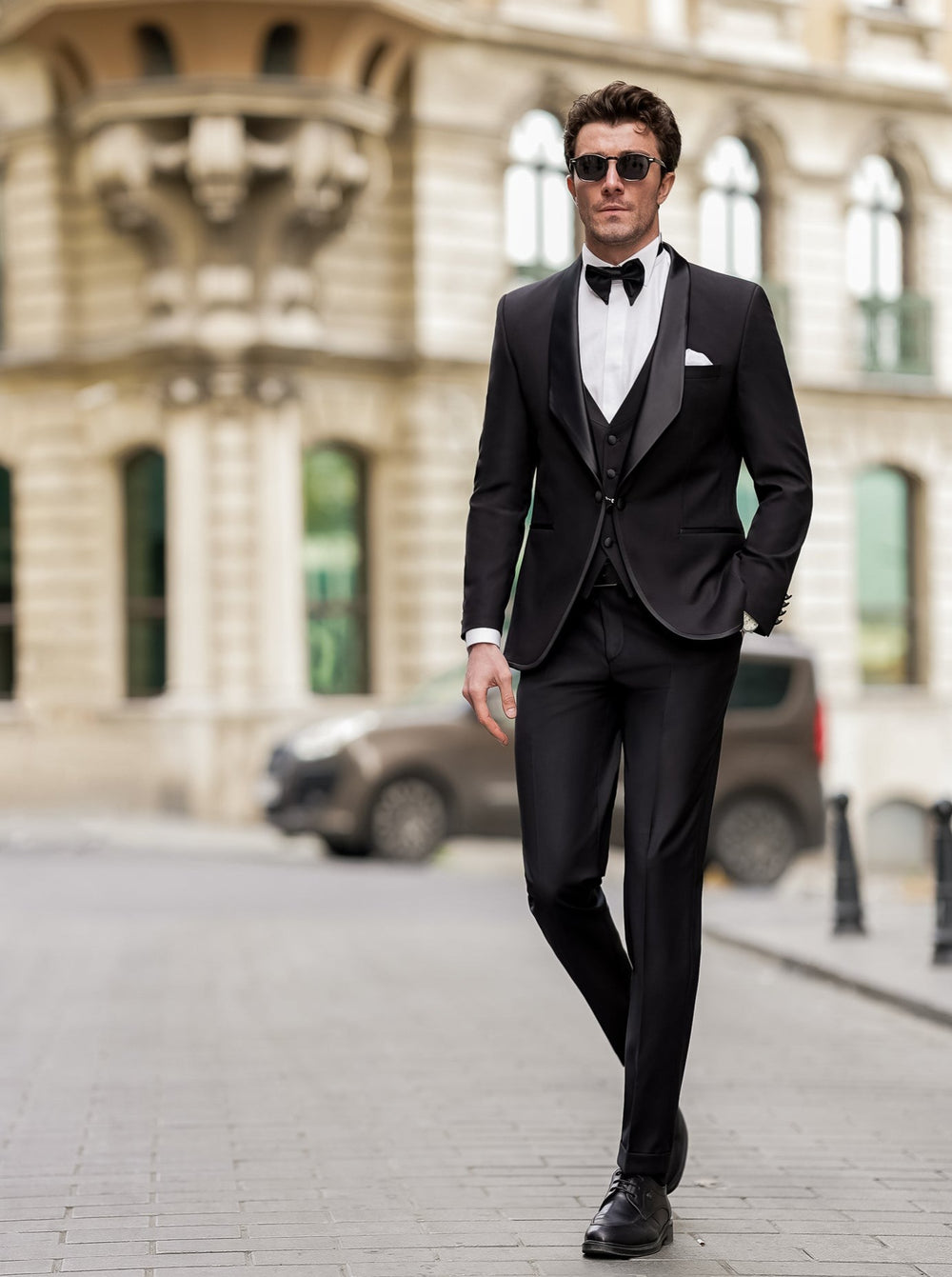 Elegant black men suit by XAYWEAR worn with white shirt and bow tie on a city street