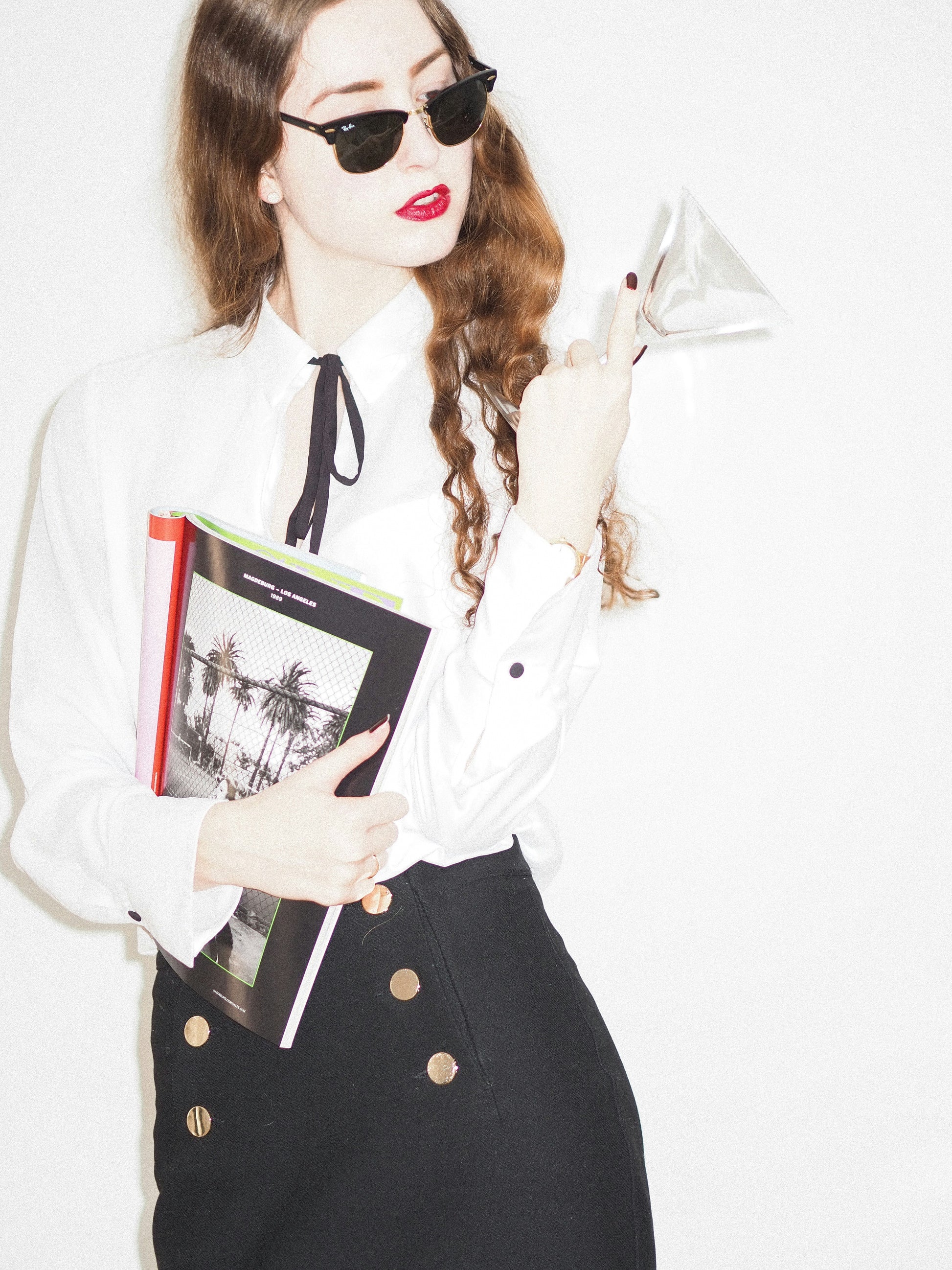 Woman wearing XAYWEAR black skirt with button details paired with white blouse and sunglasses