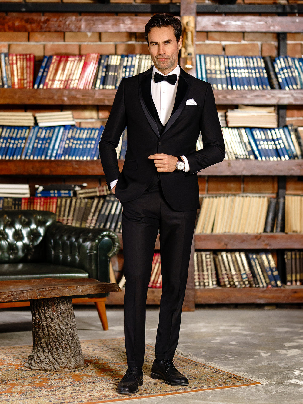 XAYWEAR elegant black suit for men with bow tie and pocket square in a classic library setting