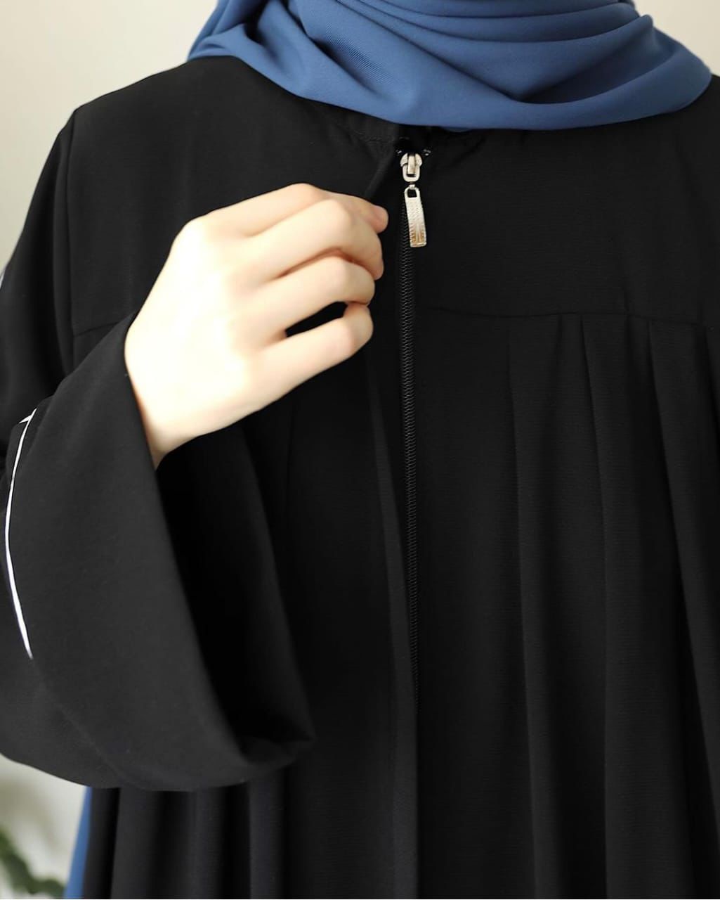 Elegant black zip neck abaya featuring a sleek design and stylish pleats for modern modesty