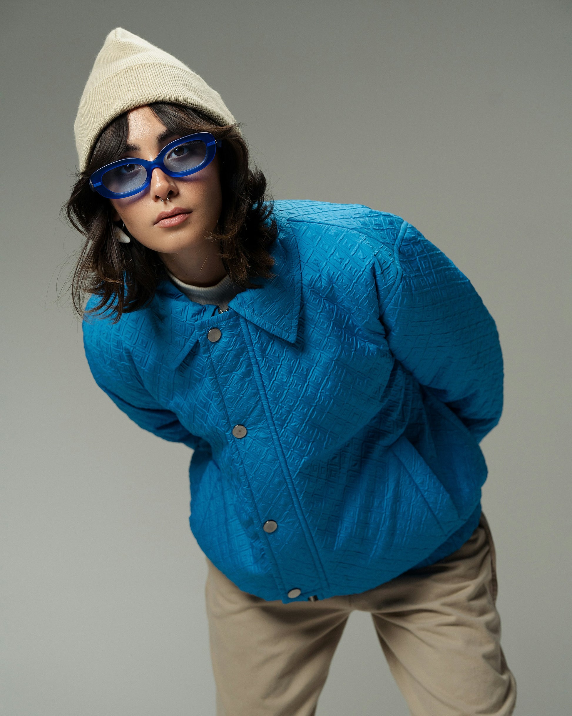 XAYWEAR blue quilted winter jacket worn by woman with beige hat and blue sunglasses