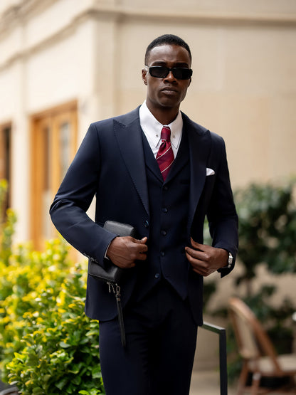 Stylish man wearing a blue suit for men by XAYWEAR with white shirt and red tie outdoors