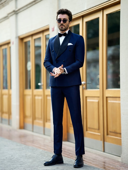 Man wearing a stylish blue suit for men by XAYWEAR with black bow tie and sunglasses