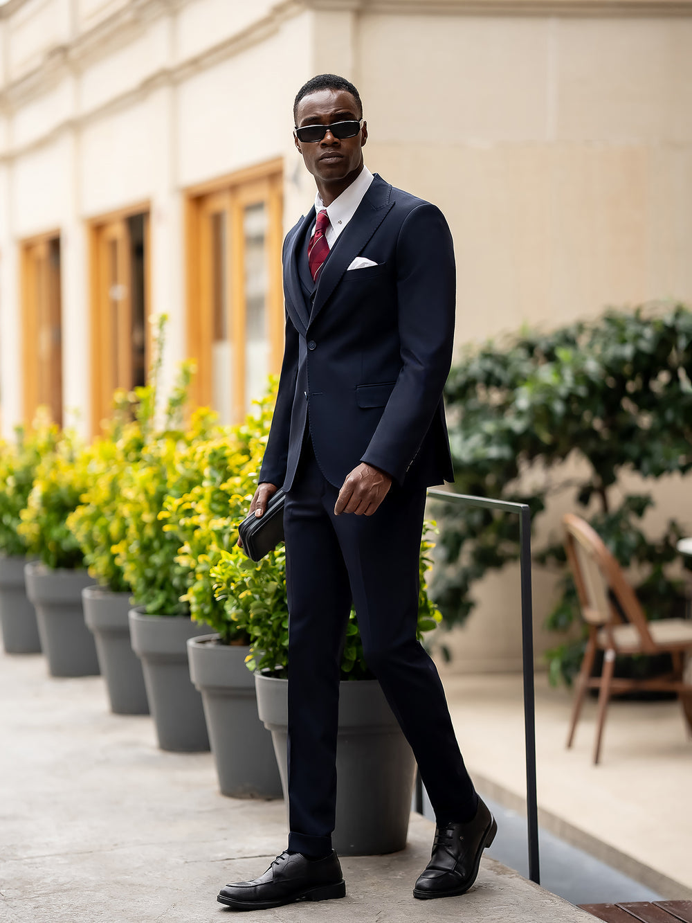 Stylish blue suit for men by XAYWEAR worn with sunglasses and red tie in an outdoor setting