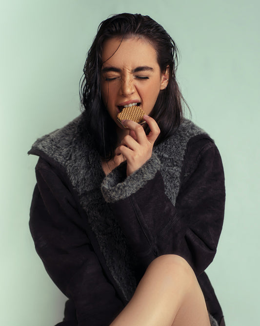 XAYWEAR winter coat for women in dark color with soft fur collar worn by woman eating cookie