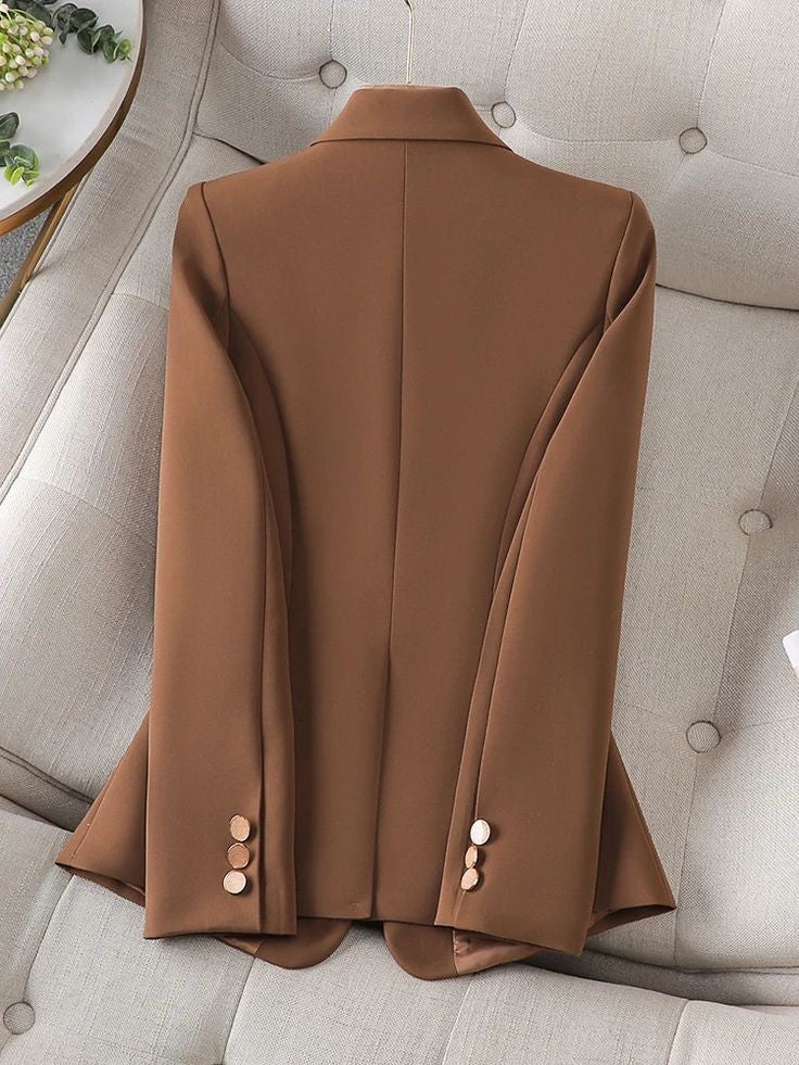 XAYWEAR brown women blazer laid flat on beige tufted sofa showing back design with buttons on sleeves