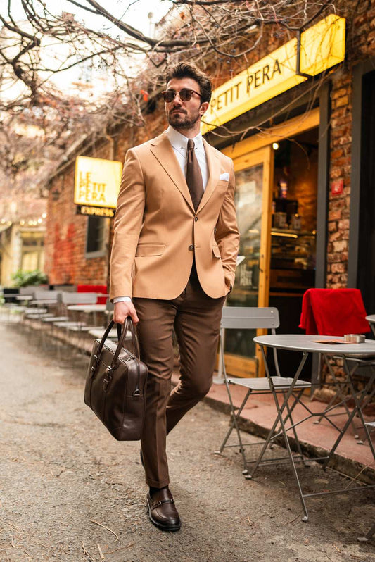 Man wearing a camel blazer and brown pants suit for men by XAYWEAR walking outdoors with a leather briefcase