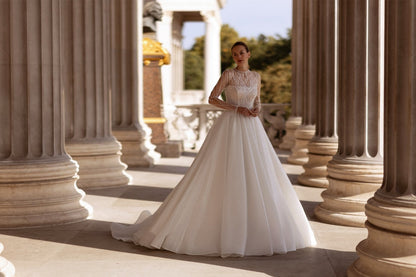XAYWEAR elegant bridal gown with lace bodice and long flowing skirt in outdoor columned setting