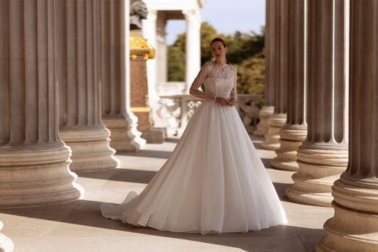XAYWEAR elegant bridal gown with lace bodice and long flowing skirt in outdoor columned setting