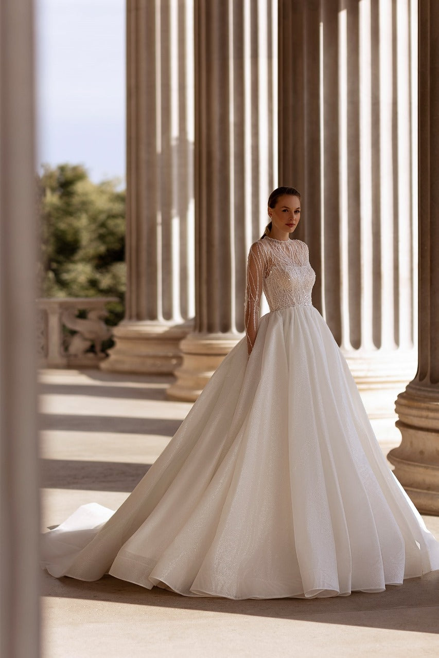 Elegant XAYWEAR bridal gown with lace bodice and full flowing skirt in a classical architectural setting
