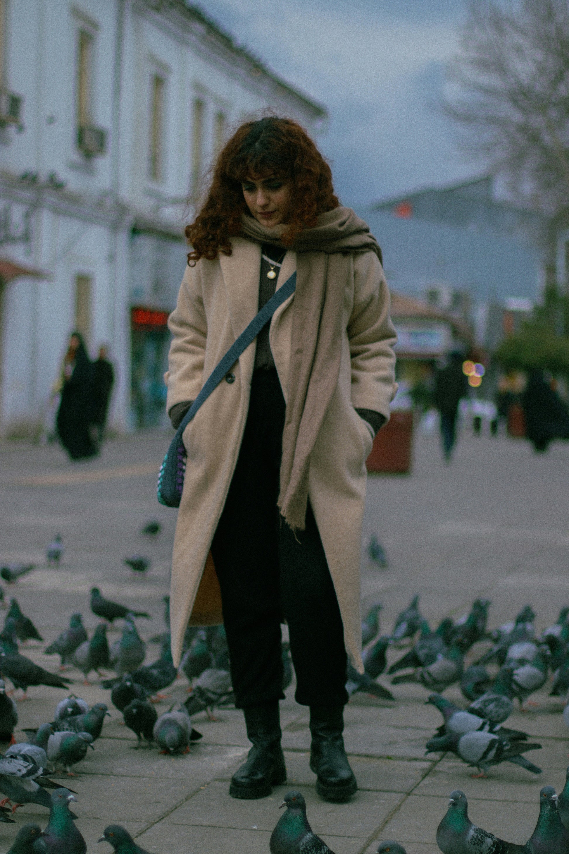 Elegant beige overcoat from XAYWEAR worn by a woman on a street surrounded by pigeons