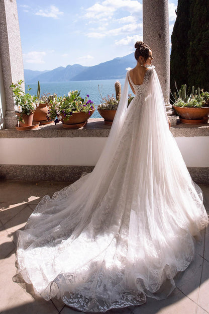 XAYWEAR elegant wedding dress with long train and lace details on a bride by a scenic balcony