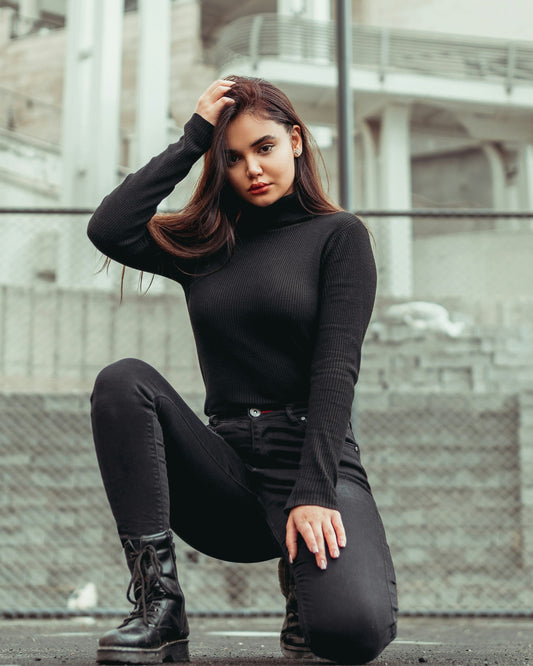 Model wearing a fitted black knit turtleneck paired with black jeans and combat boots