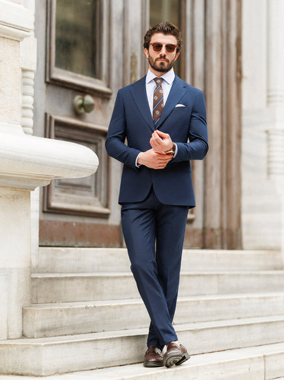 XAYWEAR formal wedding suit in navy blue worn by a man with sunglasses standing on stone steps