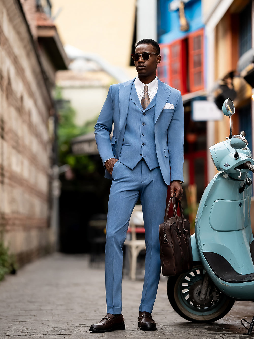 Man wearing a stylish light blue suit for men by XAYWEAR paired with sunglasses and brown shoes